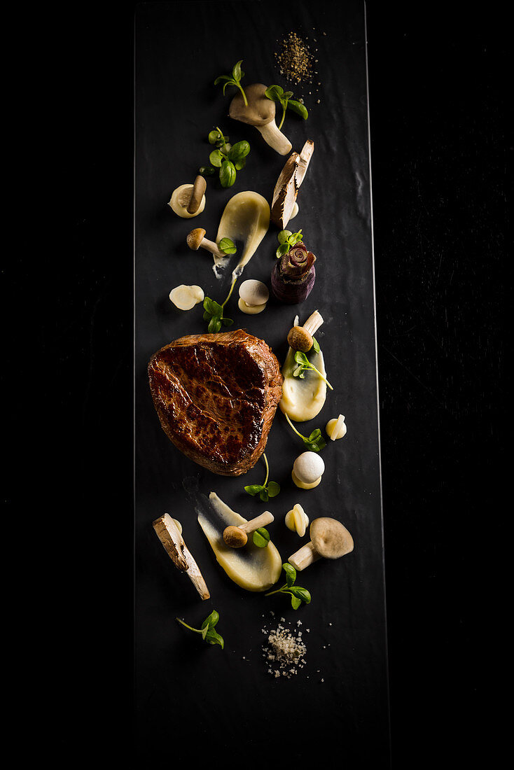 Beef steak with mushrooms on a black surface