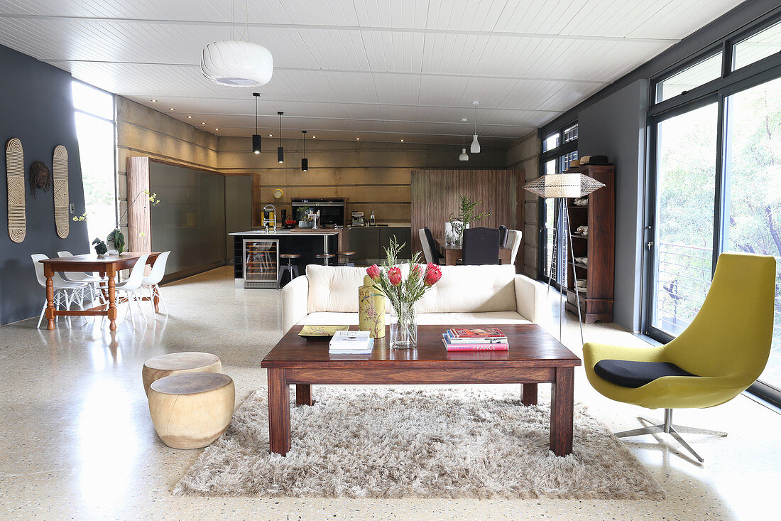 Coffee table, designer easy chair and sofa in open-plan interior