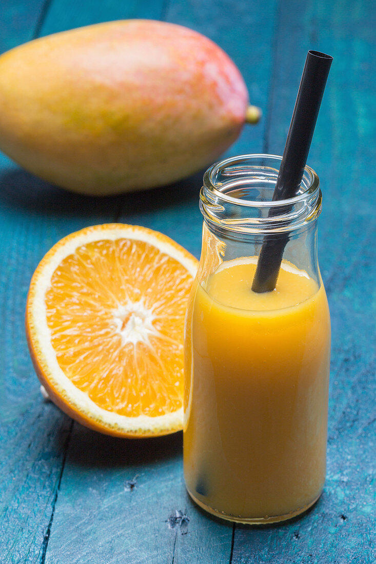 Mango-Orangen-Smoothie in einer Flasche mit Strohhalm