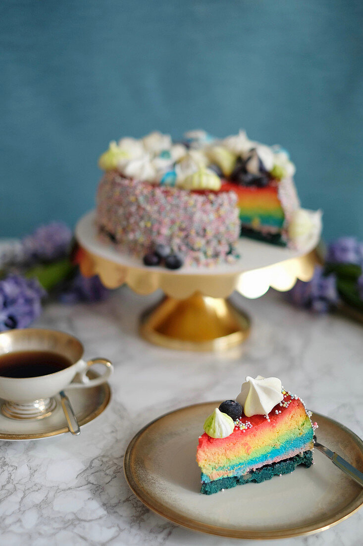 Regenbogen-Cheesecake, ein Stück auf Kuchenteller