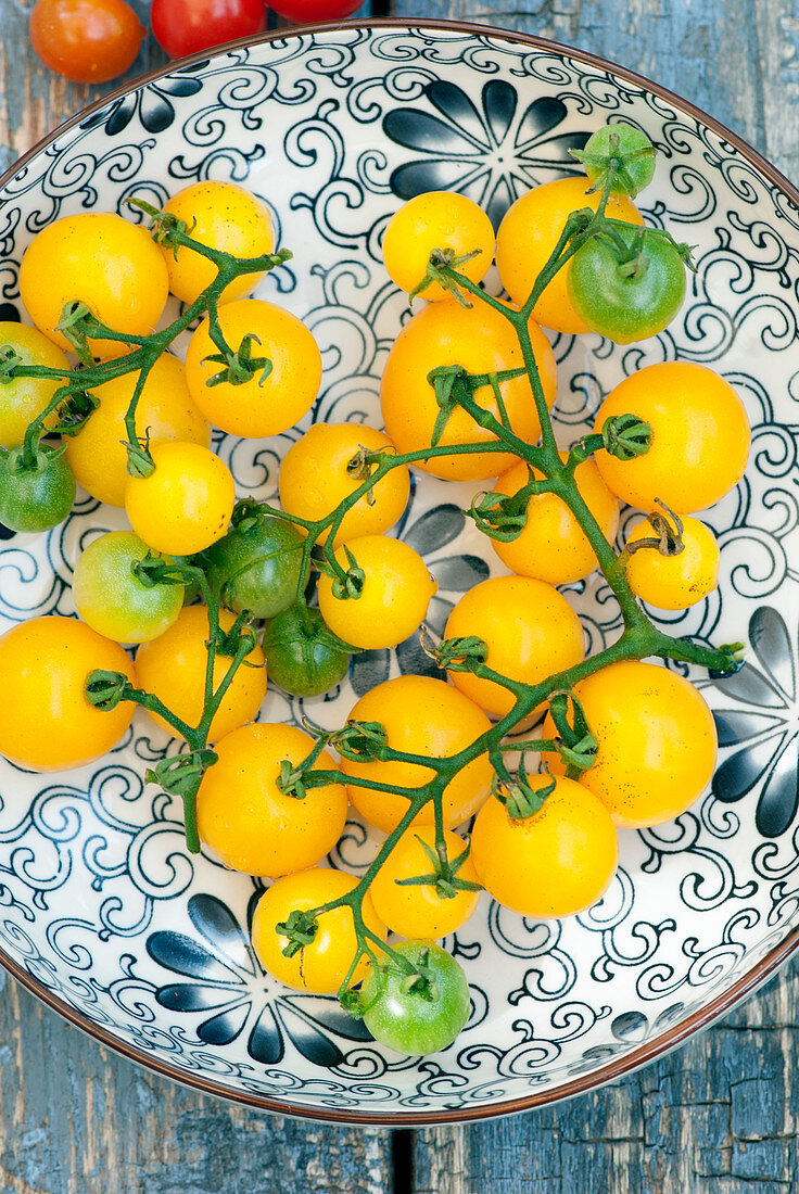 Frische gelbe Tomaten auf gemustertem Teller