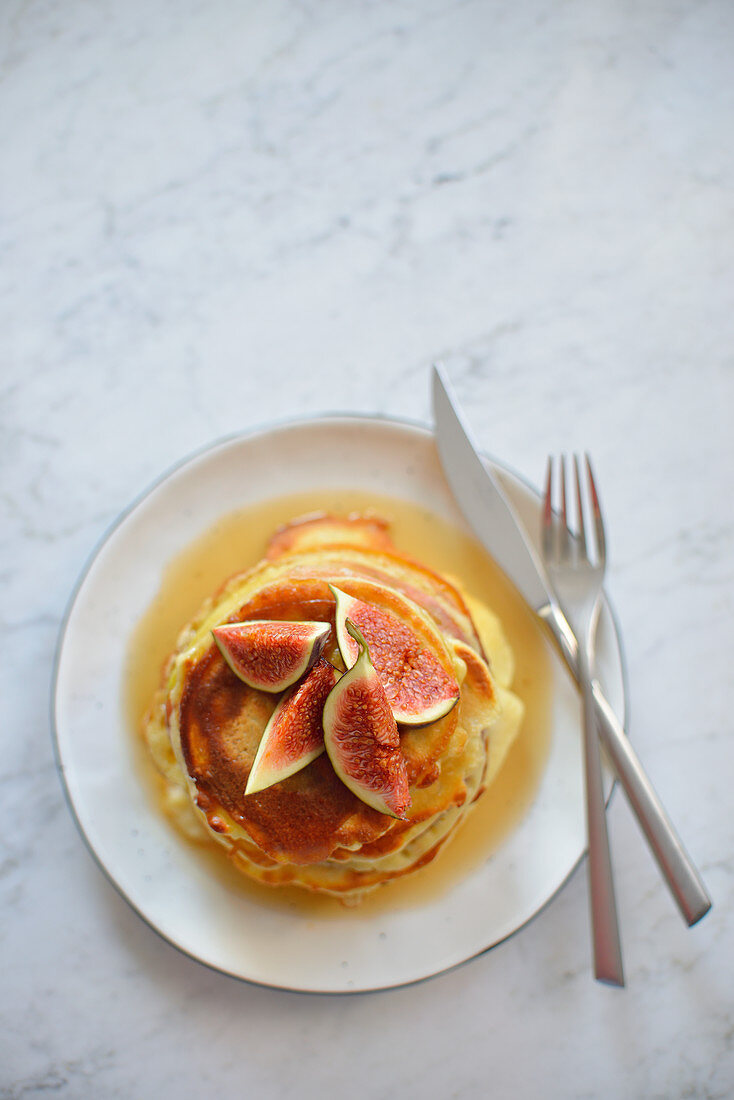 Pancakes with maple syrup served on a plate on a marble table