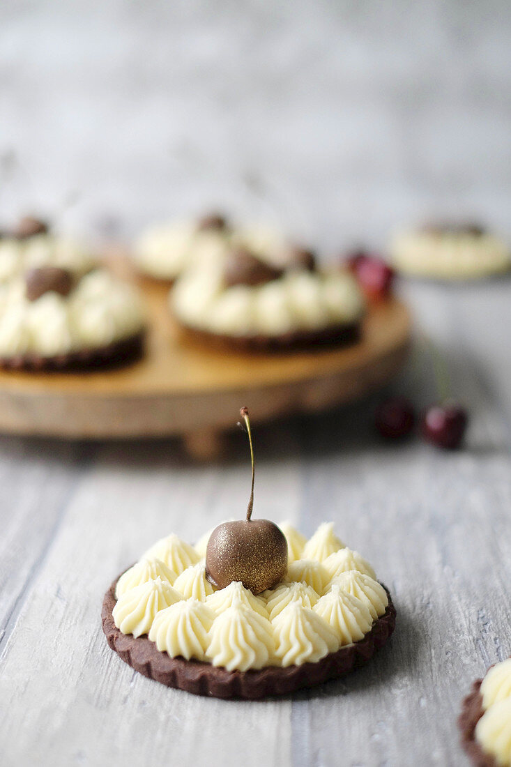 Chocolate tarts with vanilla cream and chocolate cherries