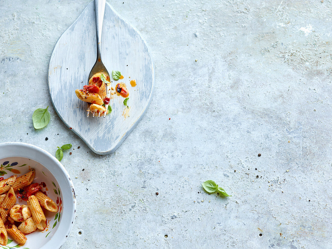 Pasta mit Tomaten und Basilikum in Schälchen und auf Gabel (Aufsicht)
