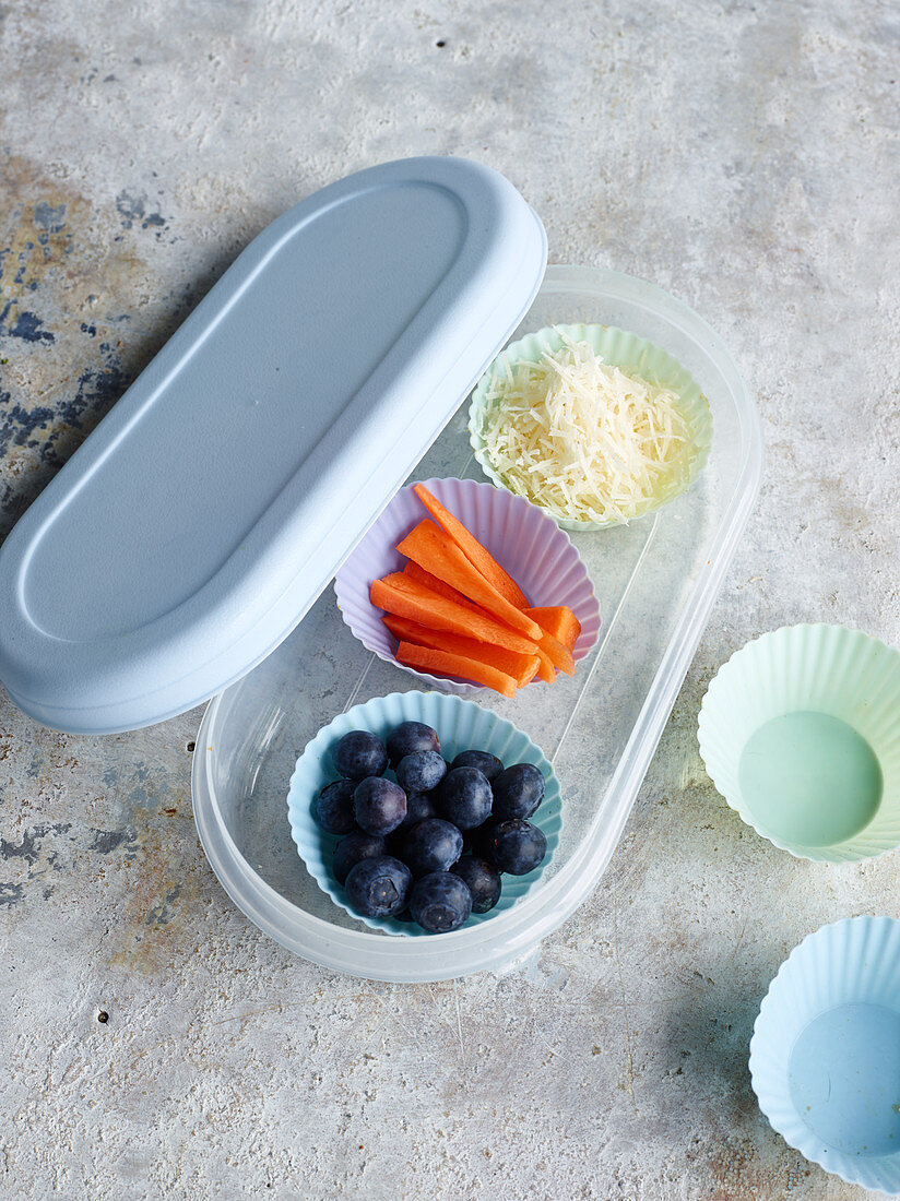 Silikonförmchen mit Käse, Karottensticks und Blaubeeren in Lunchbox