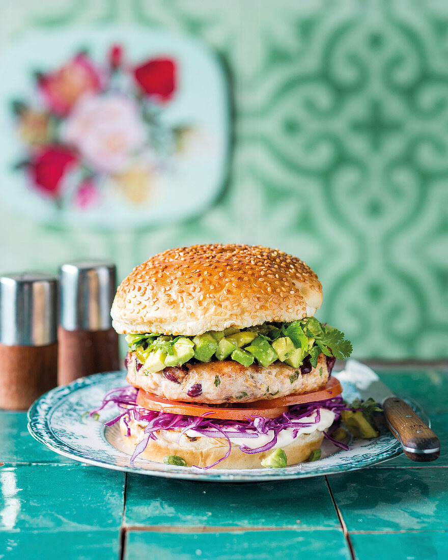 A chicken and bean burger with avocado salsa and red cabbage