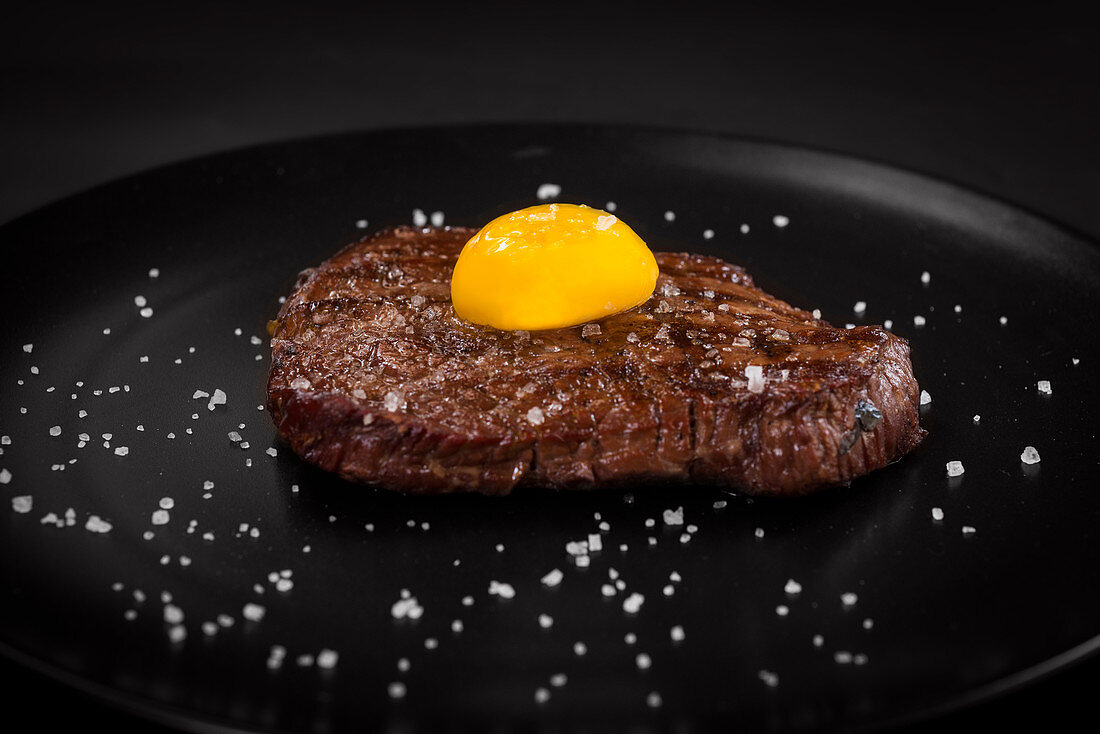 Steak mit Eigelb und Salz auf schwarzem Teller