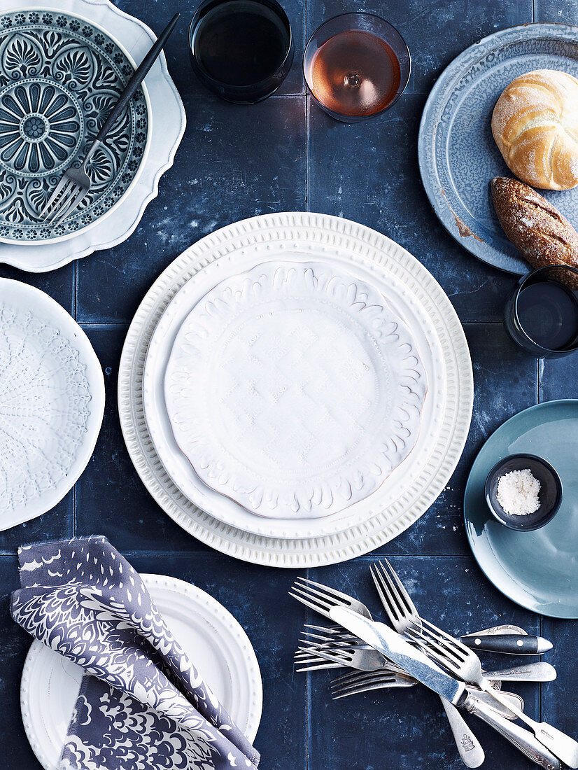 Gedeckter Tisch mit blau-weißem Geschirr, Besteck, Gläsern und Brot