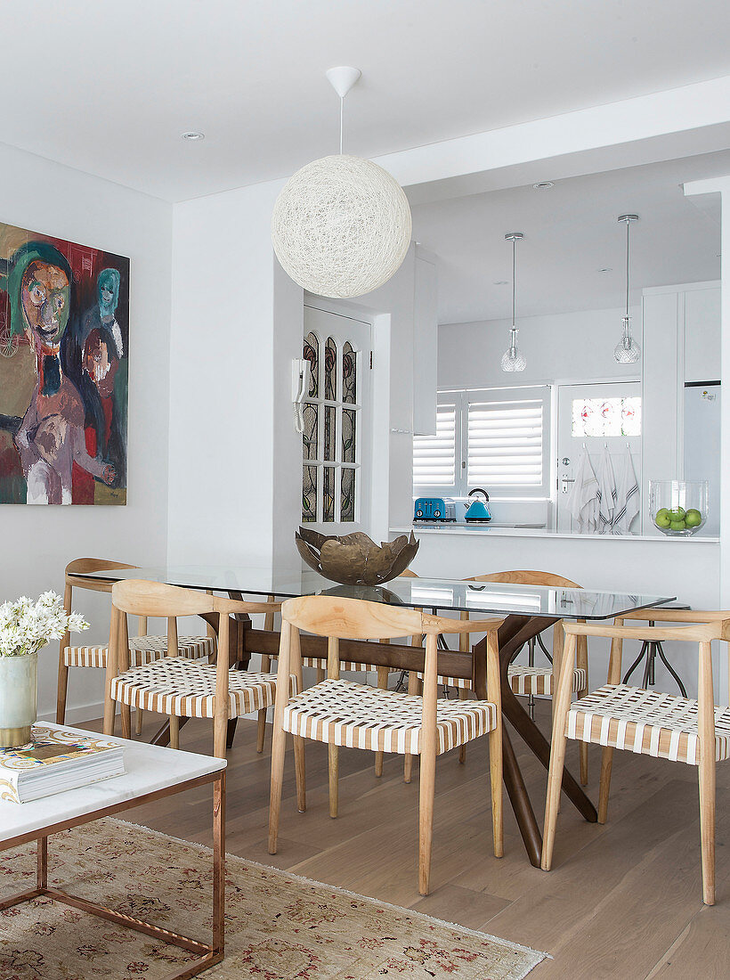 Designer chairs and glass table in dining area of open-plan interior