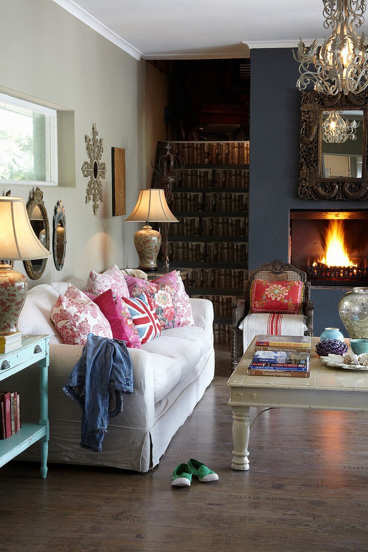 Sofa and open fireplace in living room with foot of staircase in one corner