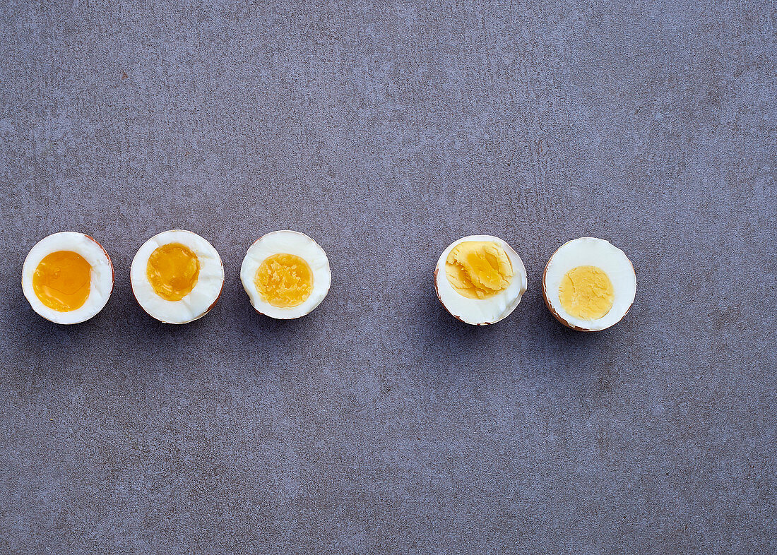 Five hard boiled egg halves on a grey background