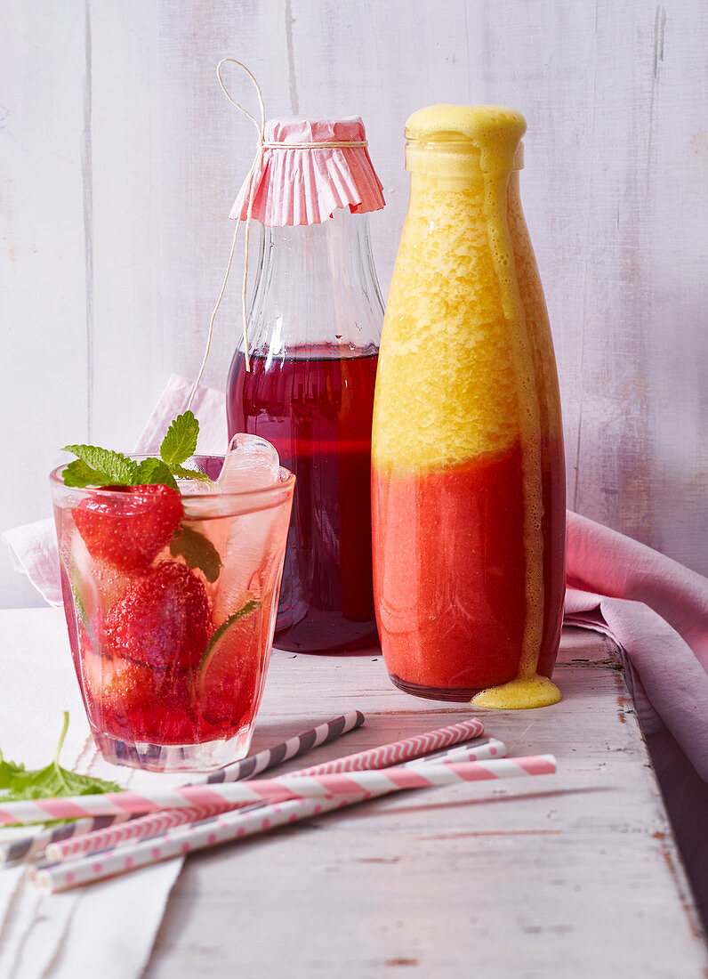 Erdbeersirup und Erdbeer-Orangen-Smoothie in Flaschen