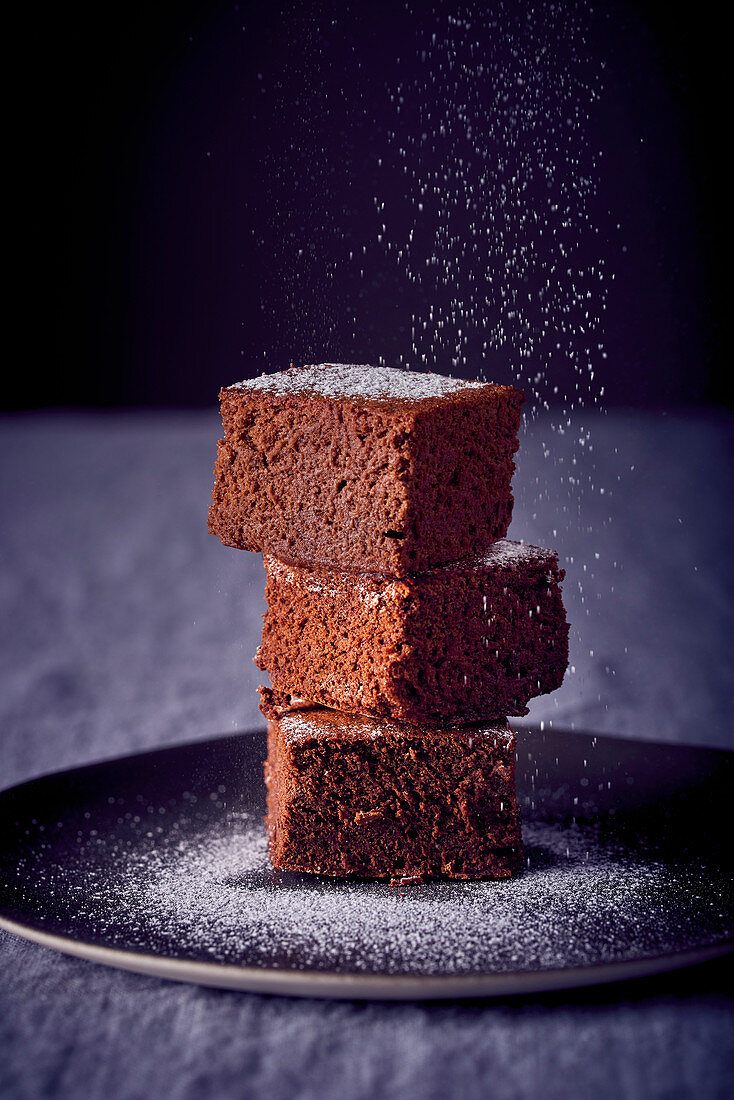 Three brownies dusted with powdered sugar