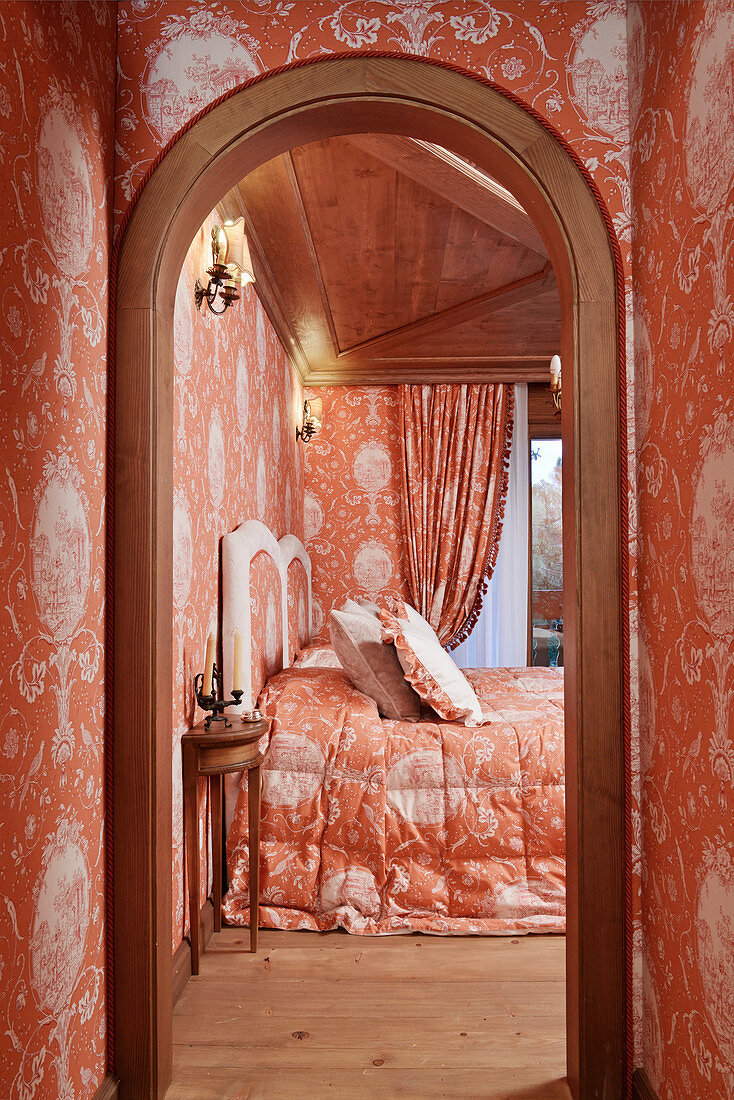 Opulent bedroom with identical orange pattern on wallpaper and fabrics