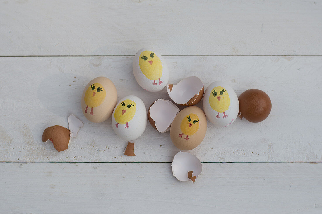 Bemalte Ostereier und Eierschalen auf weißem Holz