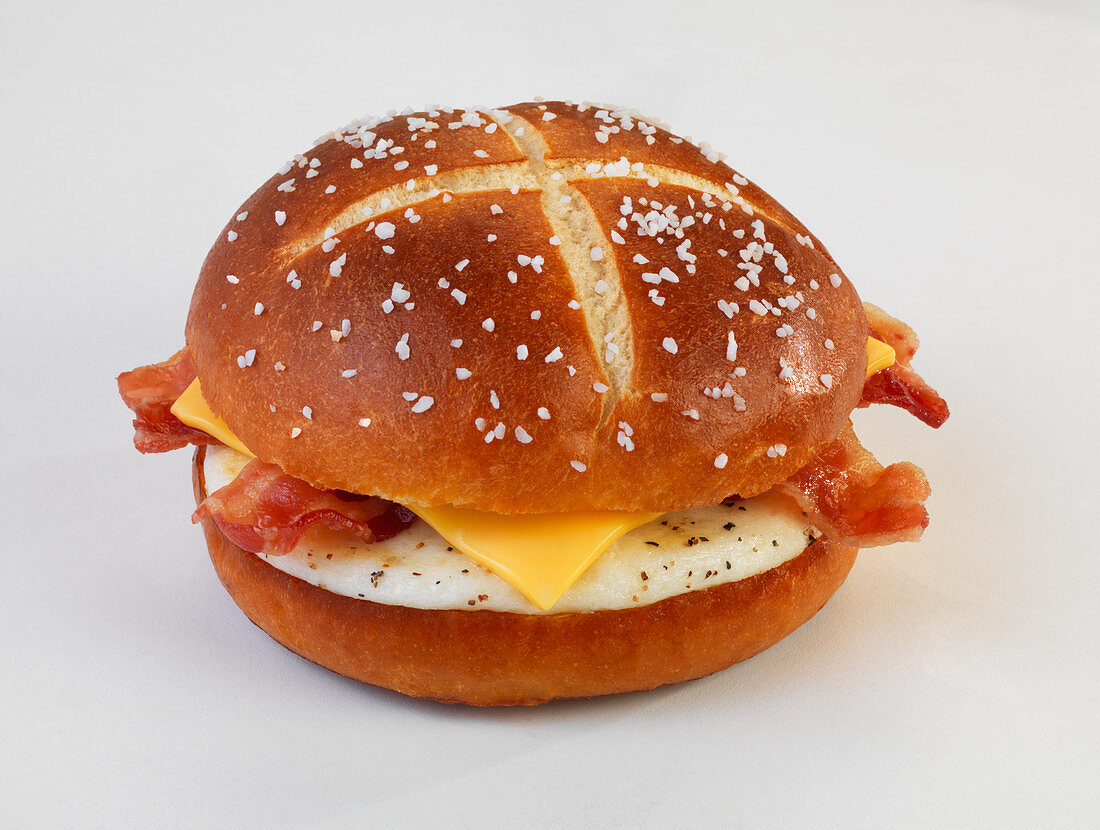 A lye bread roll with bacon, cheese and fried egg
