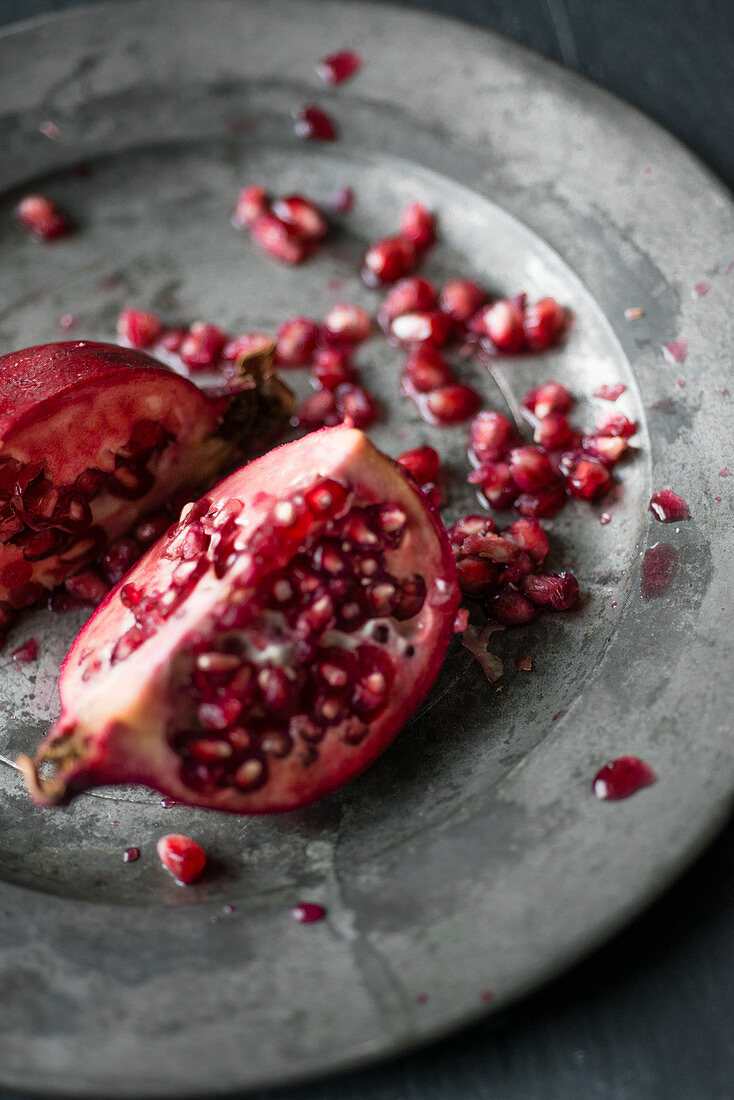 A pomegranate, sliced open, on a metal plate