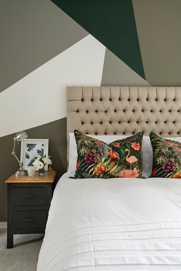 Double bed with tall headboard against wall with geometric pattern in bedroom