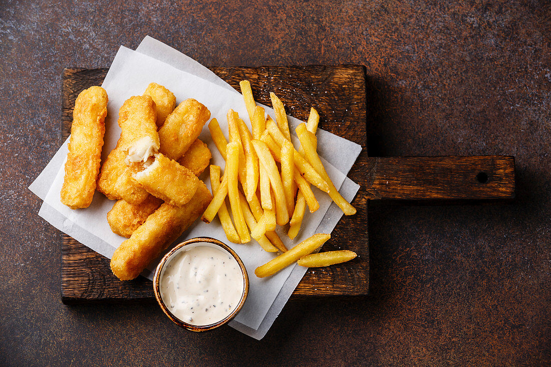 Fish and Chips mit Remoulade (Fastfood, England) auf dunklem Untergrund