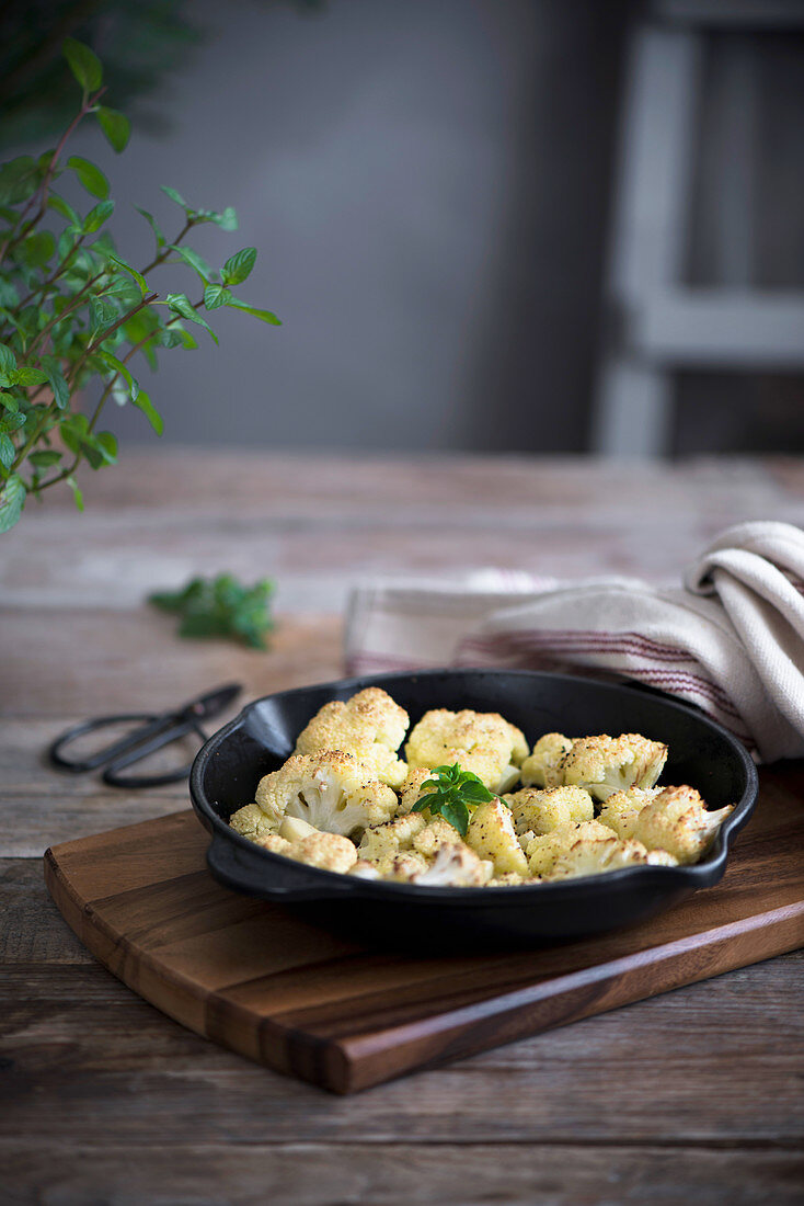 Gebackener Blumenkohl in Schale auf rustikalem Holztisch