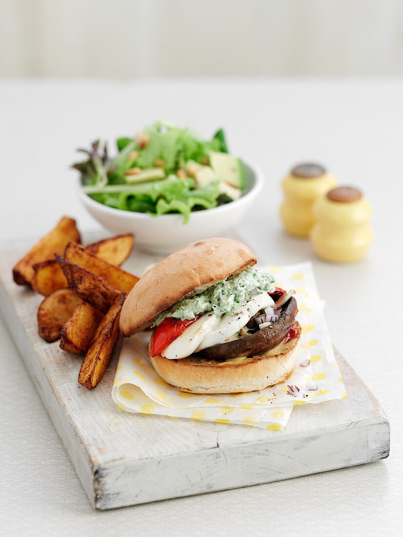 A mushroom burger with chips and salad