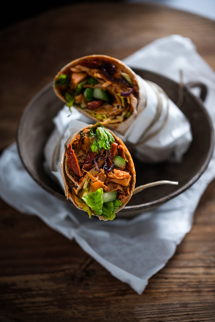 Vegan tortilla wraps filled with pulled jackfruit, dried tomatoes, red onions, cucumber and lettuce