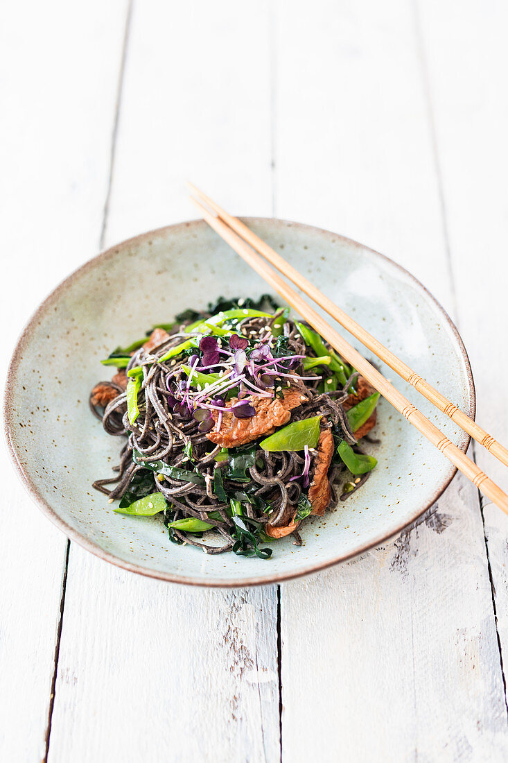 Black bean noodles with palm kale, mange tout and marinated beef