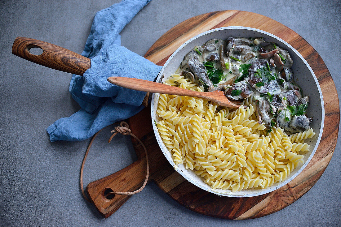 Pasta mit Pilzen in cremiger Sauce serviert in Pfanne (Aufsicht)