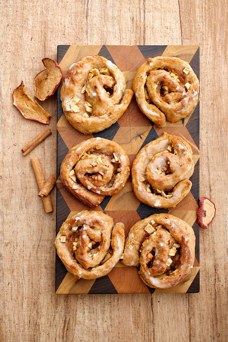 Apple and cinnamon buns on a wooden board (seen from above)