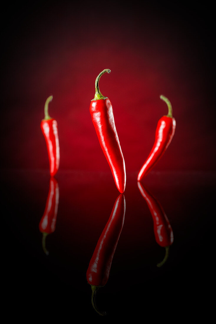 Three chilli peppers against a black and red background