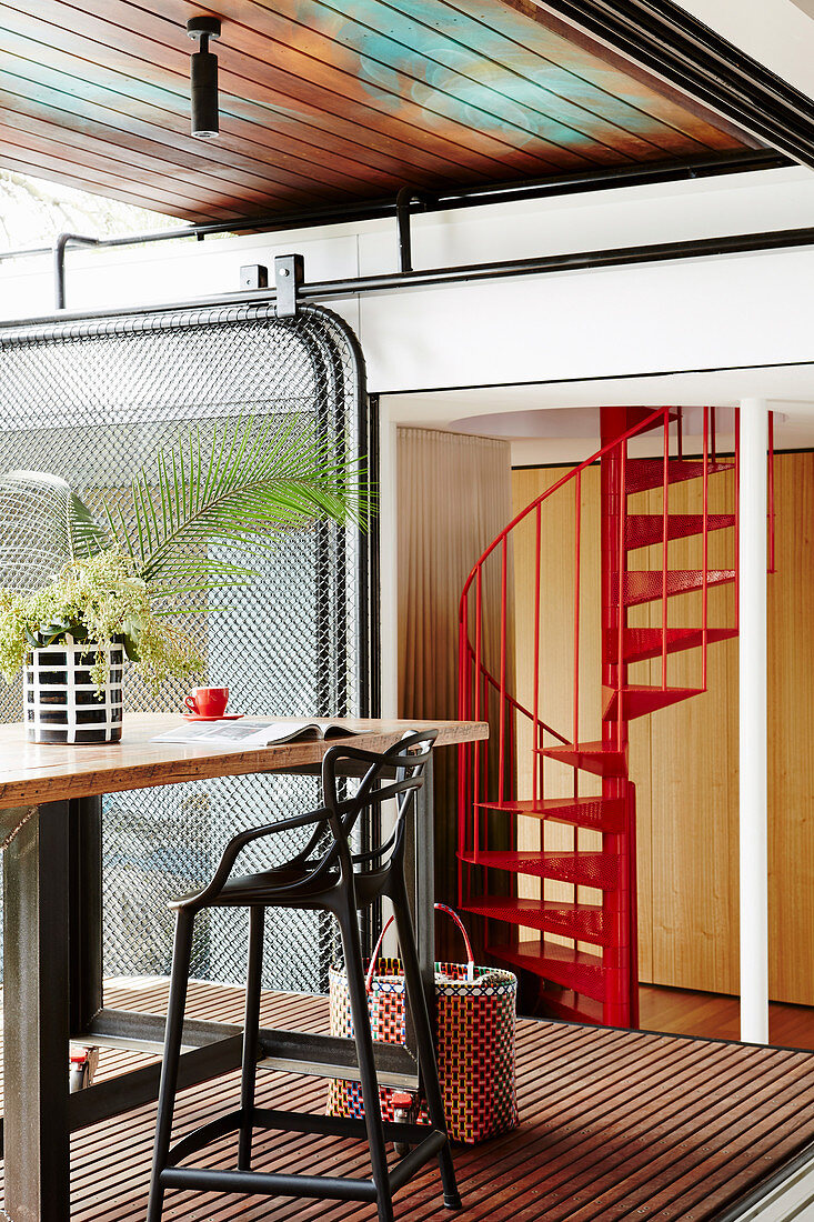 Counter table with bar stool, red painted spiral staircase in the background