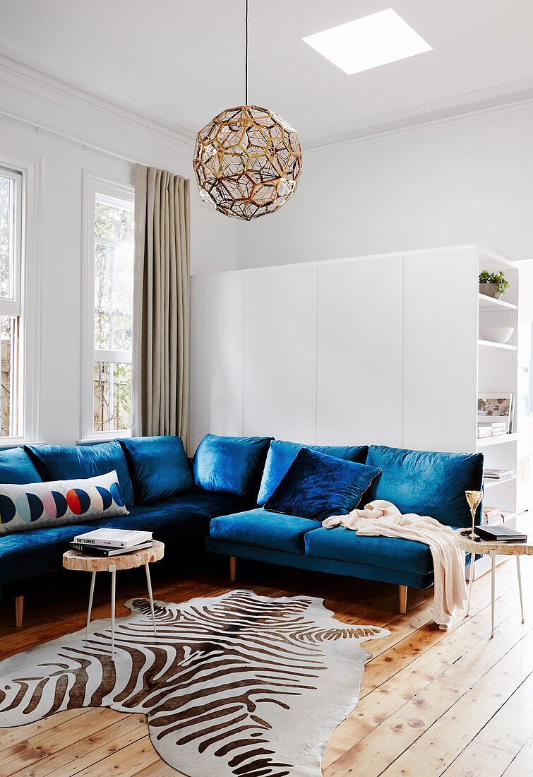 Blue seating and zebra fur in a bright living room with wooden floorboards