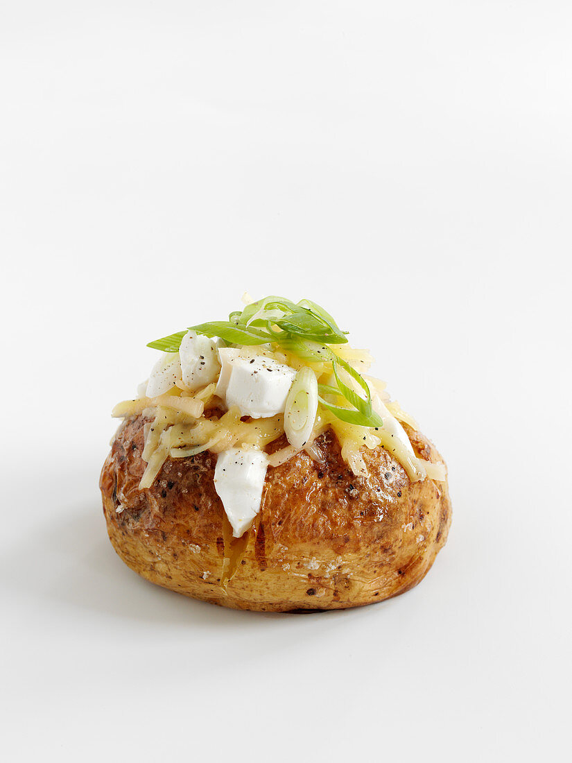 A baked potato with cheese and spring onions