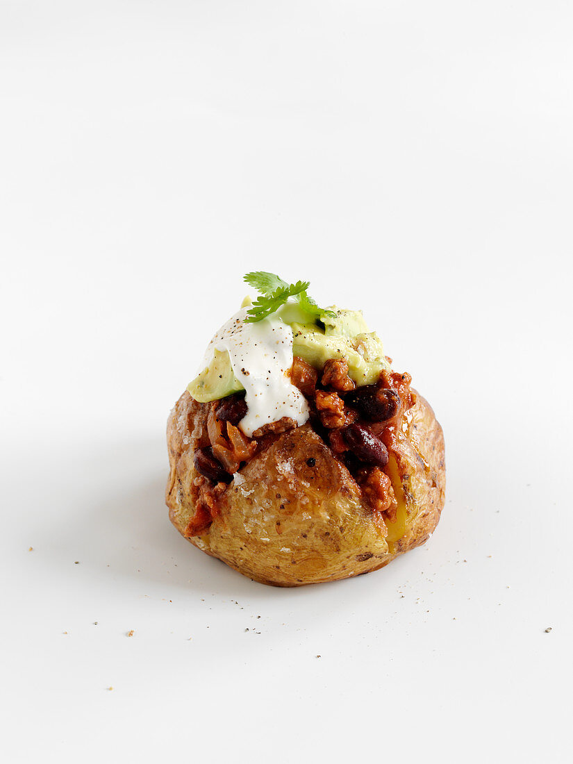 A baked potato with chili and avocado