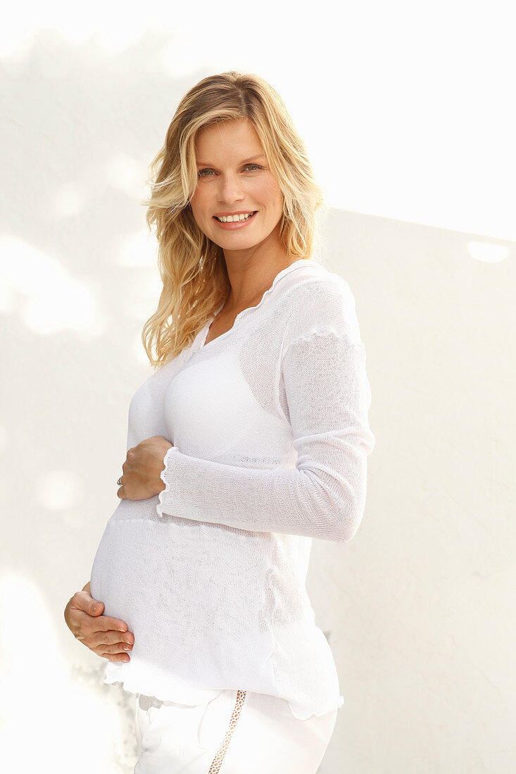 A pregnant woman wearing a white, transparent blouse