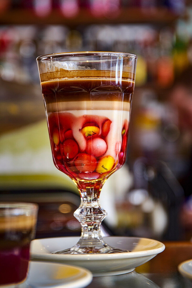 A cocoa drink with chocolate beans served in a decorative stemmed glass