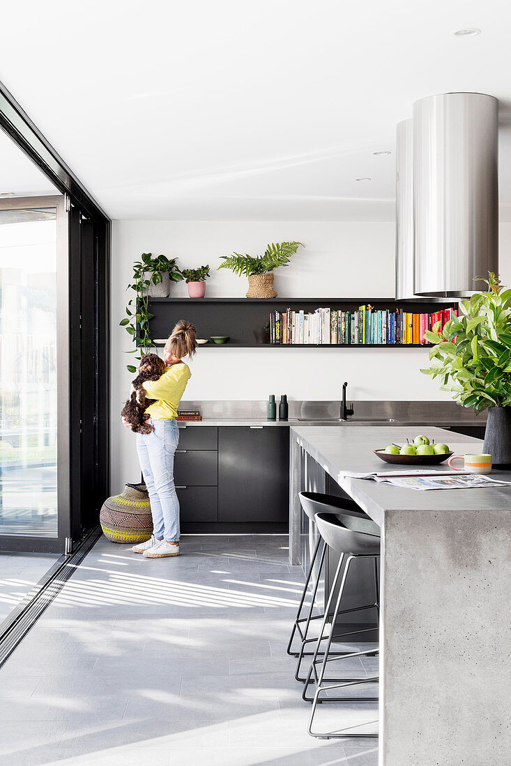 Frau und Hund stehen in moderner Küche mit Kochinsel aus Beton
