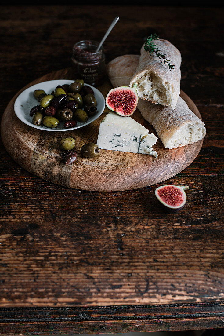 A cheese plate with bread, olives and onion jam