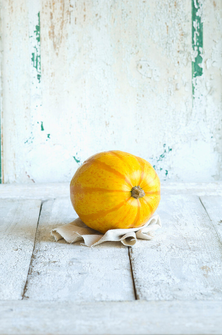 A yellow spaghetti squash against a white wooden background