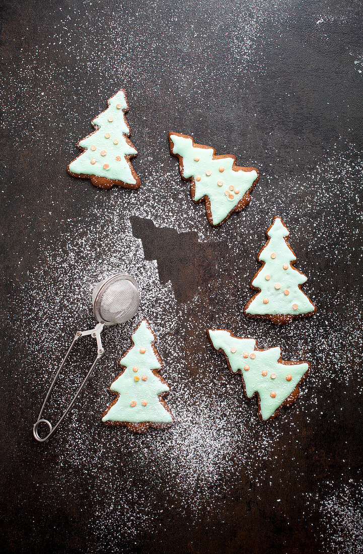 Christmas tree shaped gingerbread cookies with icing, confetti and dusted sugar on top