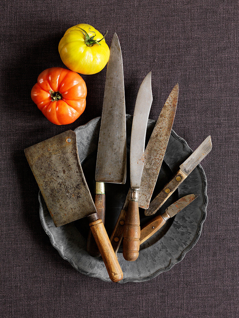 Various vintage knives on a pewter plate (top view)