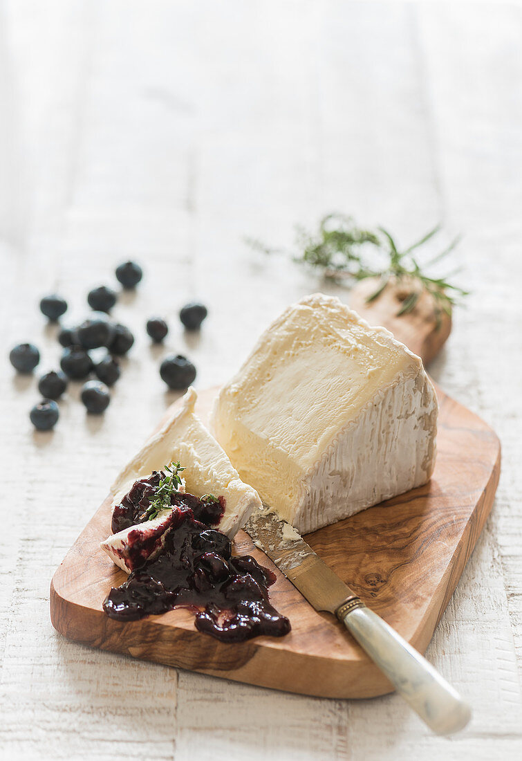 A piece of soft cheese (Delice de Bourgogne) with blueberry chutney on a wooden board