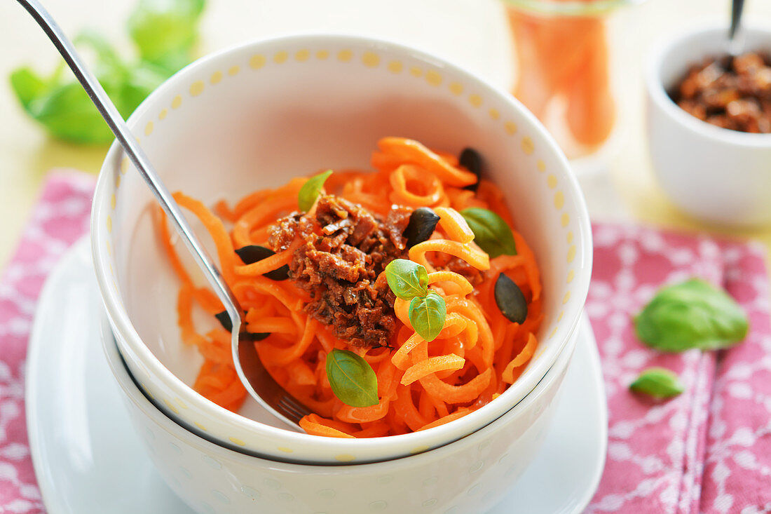 Carrot spaghetti with dried tomato pesto, pumpkin seeds and fresh basil