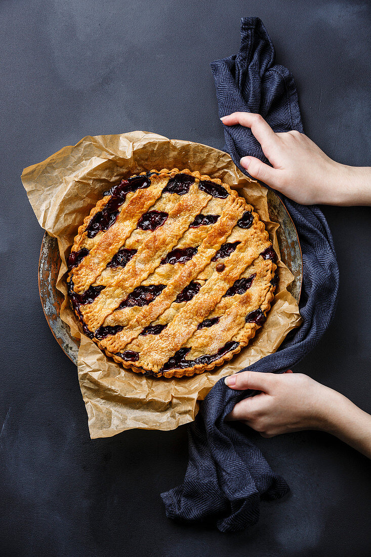 Cherry Pie and female hands on blackboard slate background