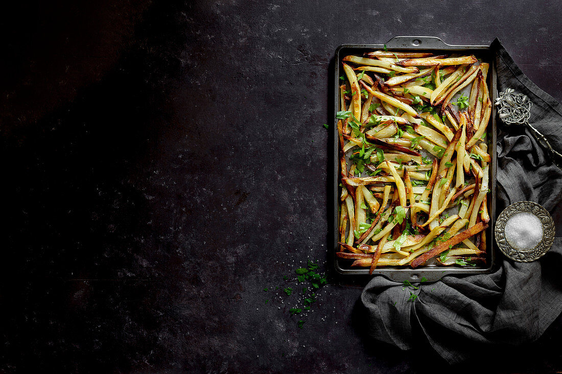 French fries on an oven tray with a black background (top view)