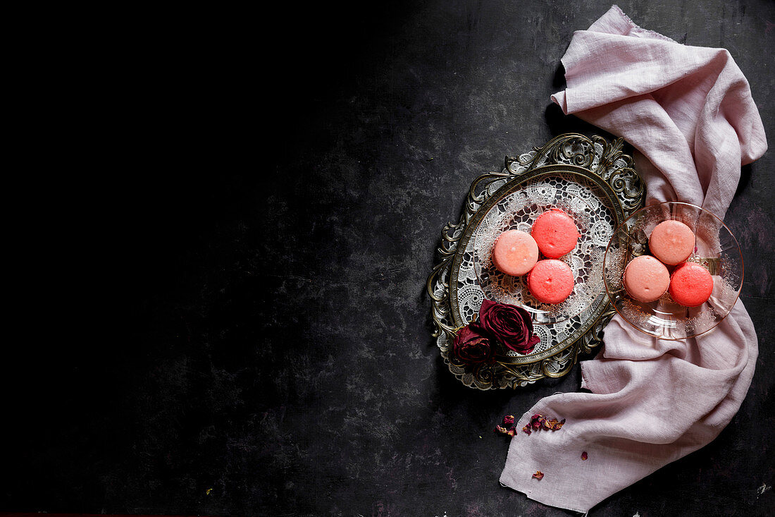 Macarons on a silver platter against a dark bckground