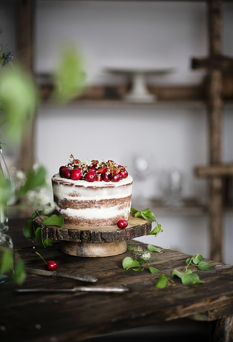 Naked chocolate cake with cherries on wooden table