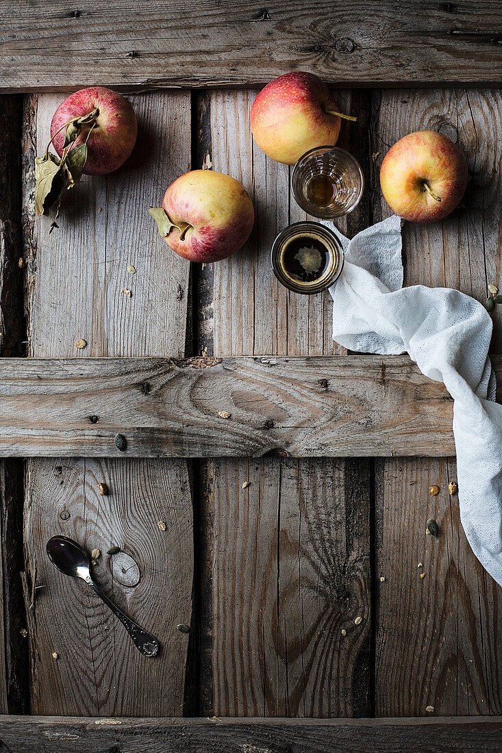 Stillleben mit Äpfeln und Kaffee in Gläsern auf rustikalem Holzuntergrund