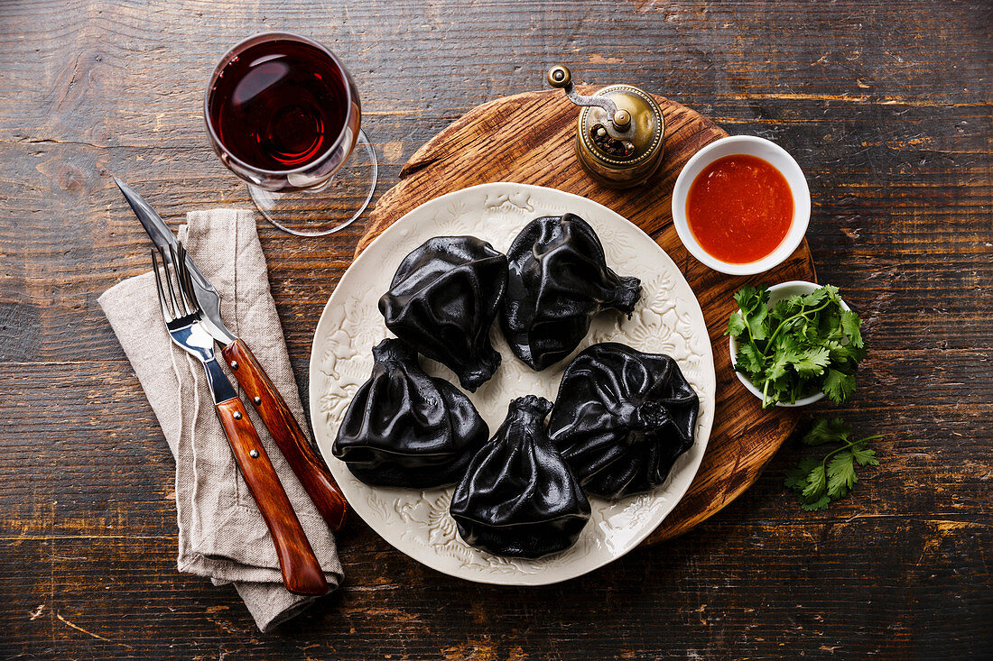 Schwarze Chinkali (Knödel, Georgien) mit Tomatensauce und Wein