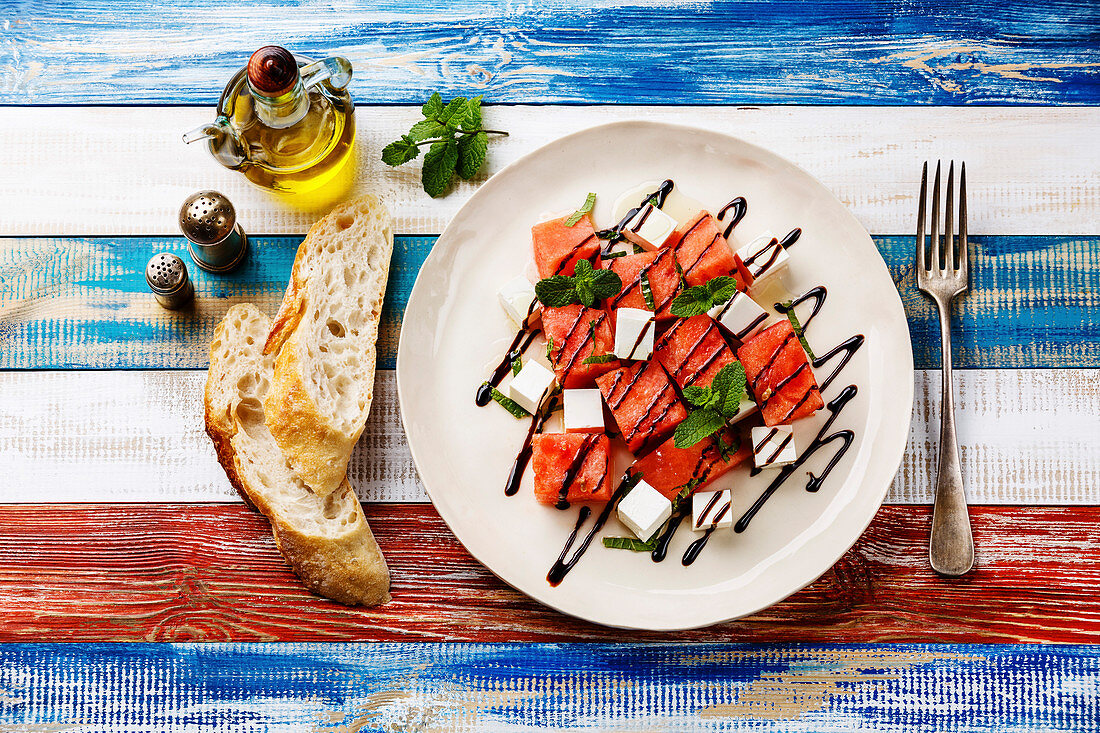 Watermelon salad with feta cheese, balsamic sauce and mint on wooden background